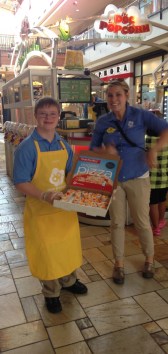 Photo of Jack serving samples of popping pizza popcorn at Doc Popcorn in Boulder Colorado. He is pictured with Doc Popcorn Trainer, Hannah McKay.